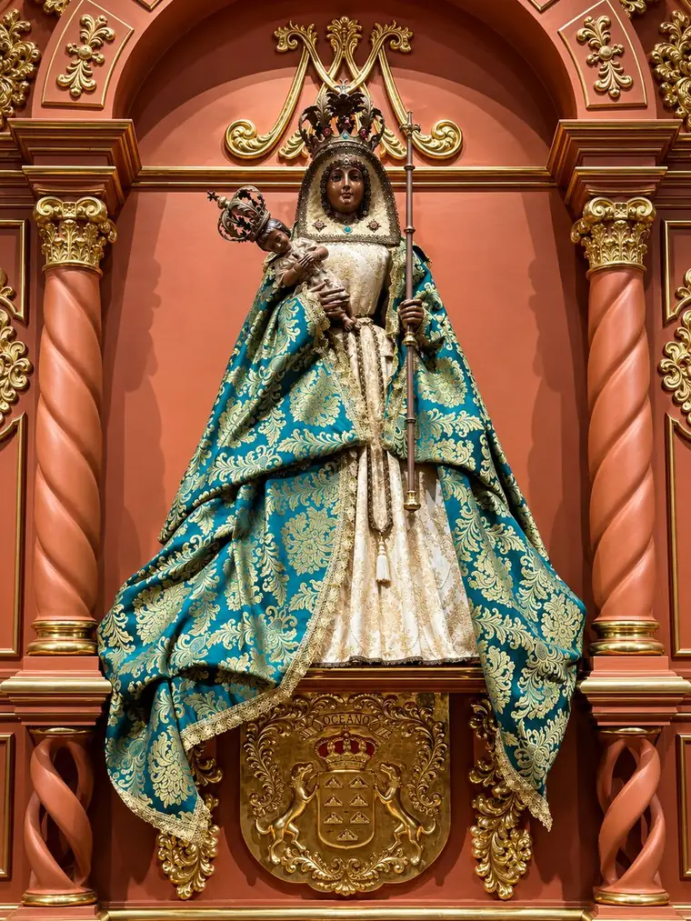 Nuestra Señora de la Candelaria in her coral and gold retablo: a dark-featured Virgin crowned, in a teal and gold brocade mantle, holding the Christ Child and a silver sceptre, above a gilded shield bearing seven islands, two dogs and the word OCÉANO.